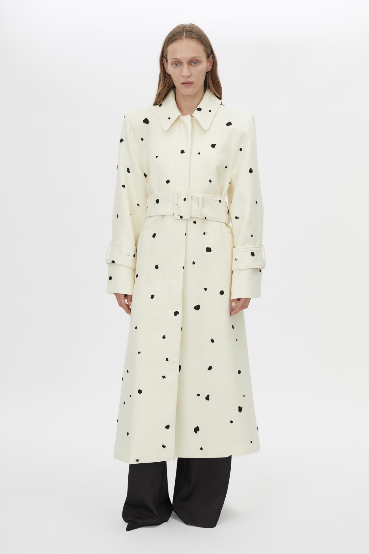 Front view CAMILLA AND MARC Ponza trench coat with black spot print, sculpted shoulders, raglan sleeves, and a belted waist.