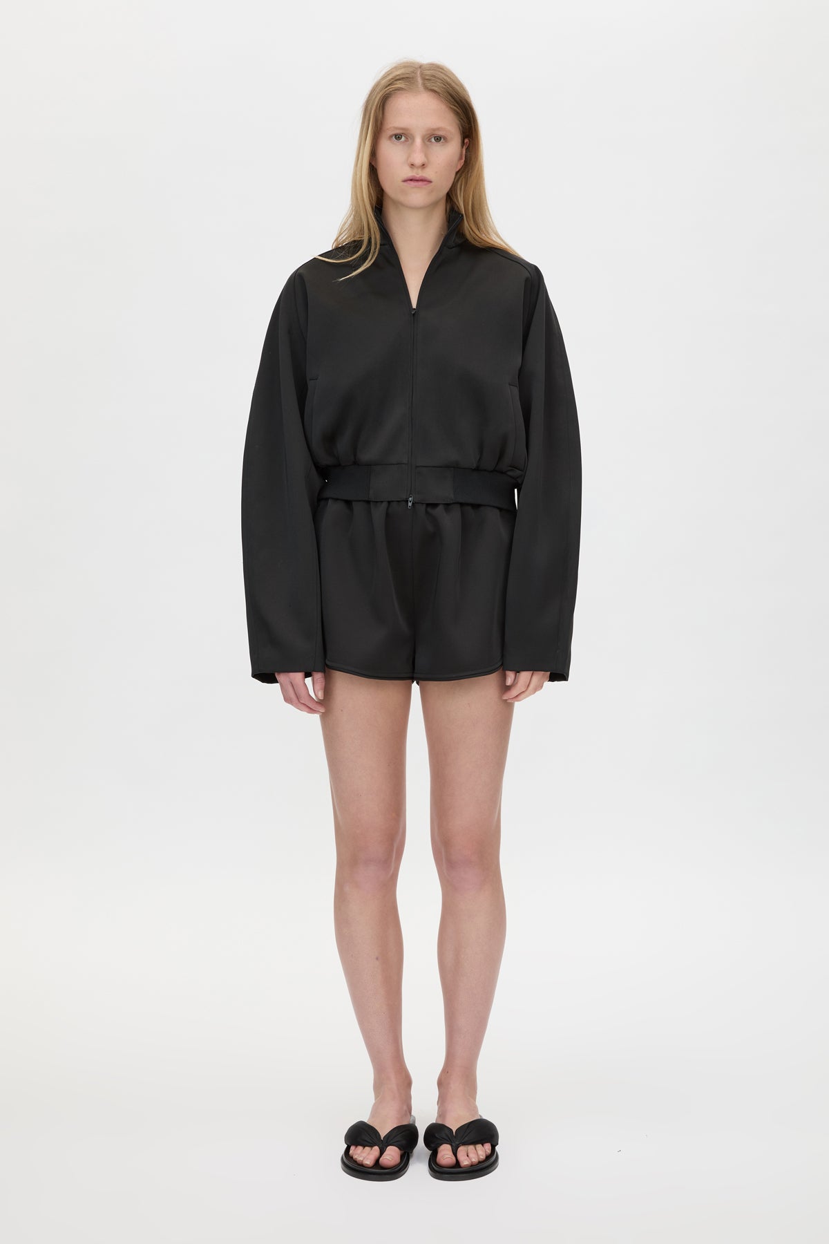 Front styled view CAMILLA AND MARC Tamar Satin Bomber Jacket in Black with front zipper.