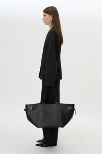 Front styled view CAMILLA AND MARC Willa Tote in Black with side strap and buckle detailing and magnetic button closure.